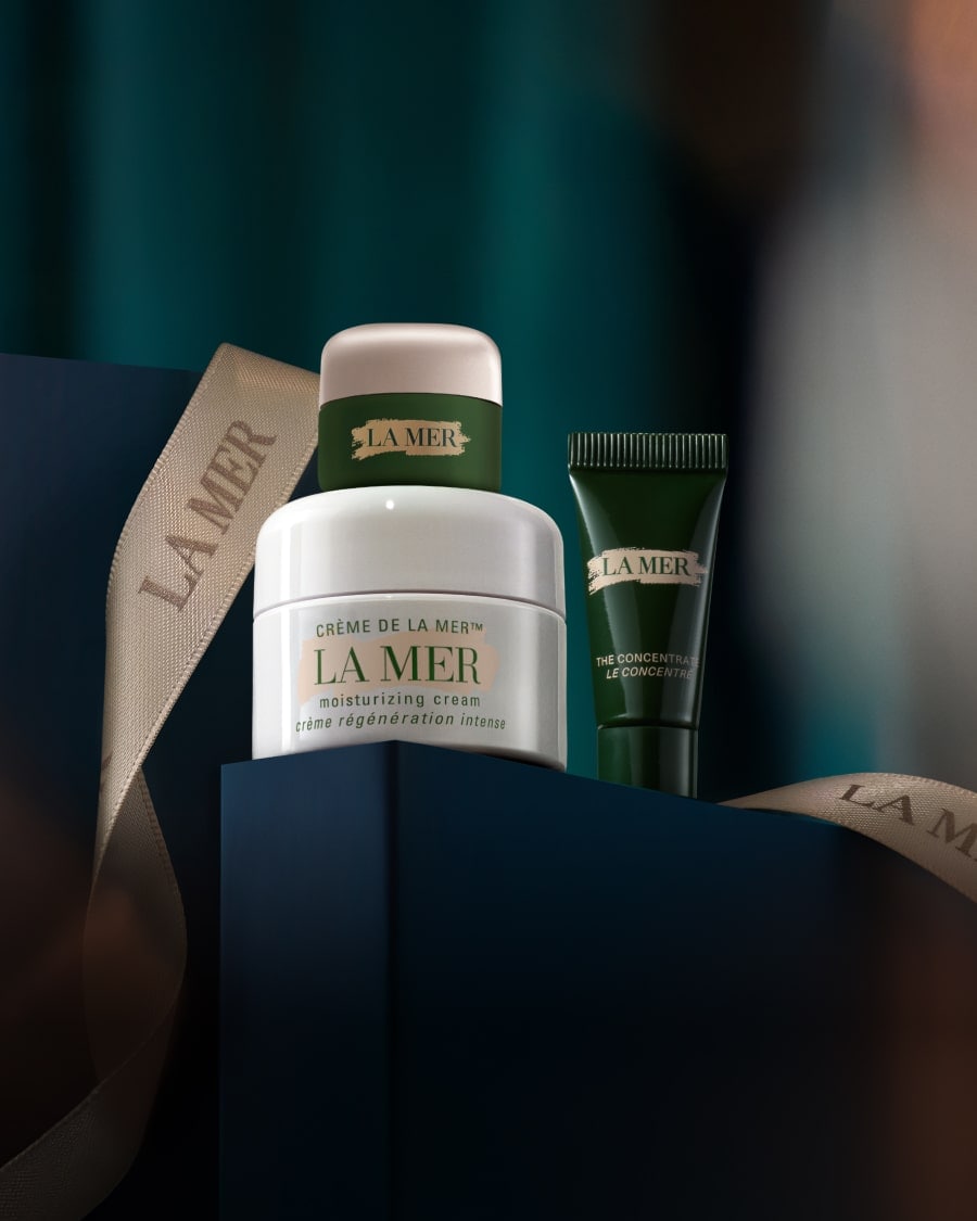Selection of La Mer minis in a dynamic, twilight lit setting, with The Eye Concentrate mini on a glass shelf